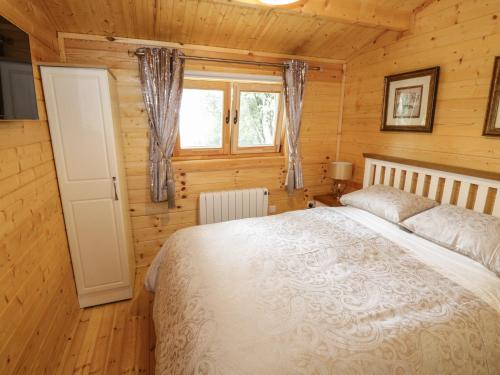 阿斯隆Port Heron Lodge的木制客房内的一间卧室,配有一张床