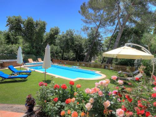 瓦尔邦讷Villa Bois Doré的一个带遮阳伞和一些鲜花的游泳池