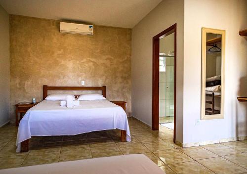 奥兰布拉Rancho da Cachaça Pousada的一间卧室配有一张带白色床单的床和一扇窗户。