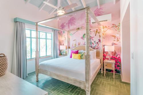 棕榈滩Boardwalk Boutique Hotel Aruba - Adults Only的一间卧室配有一张带粉红色墙壁的天蓬床。