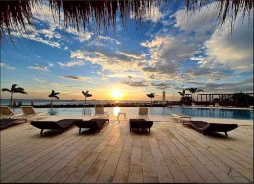 圣玛尔塔Apartasuites Samaria - Club de Playa的一个带椅子的游泳池的度假村,享有日落美景
