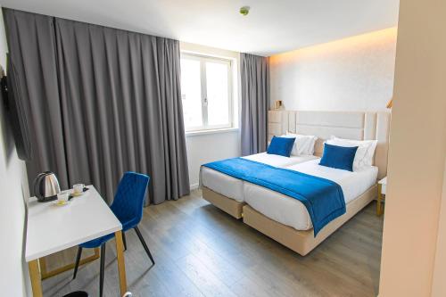 科英布拉Hotel Mondego的酒店客房带一张床、一张桌子和椅子