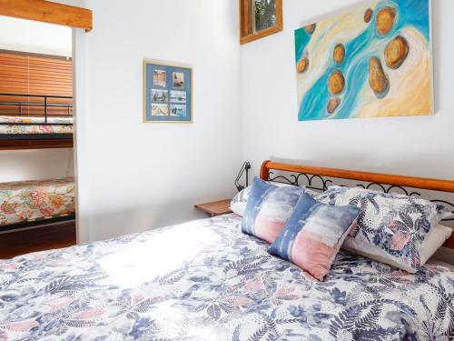 霍克斯内斯特Bennett's Beach Cottage的一间卧室配有带枕头的床铺和绘画