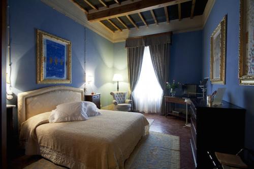 彼得拉桑塔维多米尼公寓住宿加早餐旅馆的一间卧室设有蓝色的墙壁、一张床和一张书桌