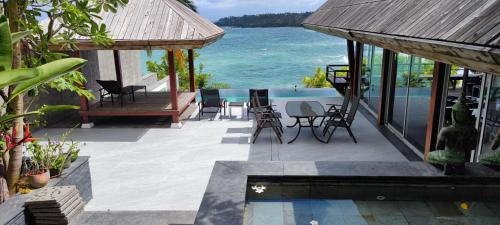苏林海滩Surin Beach Ocean front Villa between Kamala and BangTao Beaches的一个带椅子的庭院和一个毗邻大海的游泳池