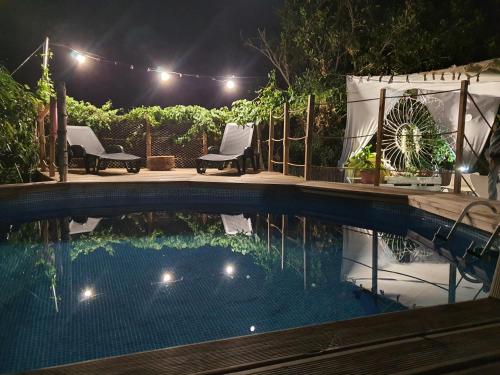 圭马尔Hotel Rural La Raya 1866的夜间游泳池,配有灯光和椅子