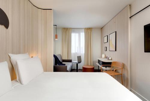 克莱蒙费朗Kyriad Clermont-Ferrand-Sud - La Pardieu的一间酒店客房,配有一张白色的床和一张书桌