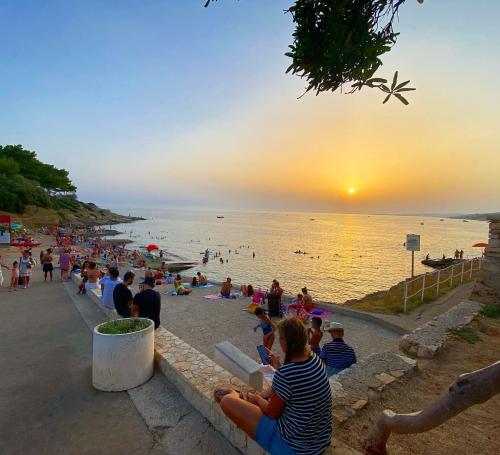 帕图Baia Salentorelax San Gregorio的一群坐在海滩上的人,看着日落