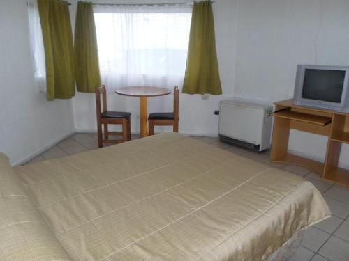 蒙特港Apart Hotel Fx的一间卧室配有一张床、一张桌子和一台电视