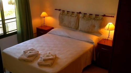 科隆Pinares de Colon的卧室配有白色床和毛巾