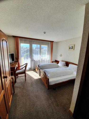 阿加恩中央酒店的一间卧室设有两张床、一张桌子和一个窗口。