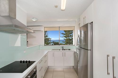 黄金海岸索尔娜玛拉海滨公寓的白色的厨房配有水槽和冰箱