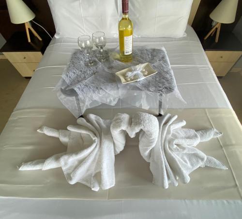 亚历山德鲁波利斯Alexander Apartments的一张带桌子的床铺、毛巾和一瓶葡萄酒
