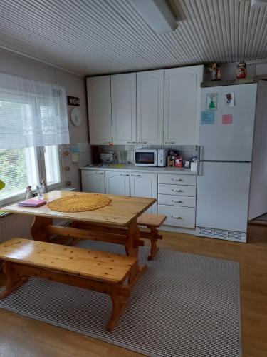 Esterin Tupa, Alajärvi的厨房配有带长凳的木桌和微波炉