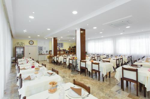 里米尼杜拉克酒店的一间设有白色桌椅的用餐室