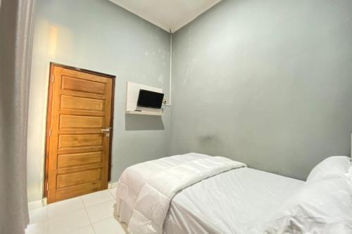 Talang KelapaPelangi Guest House Palembang RedPartner的一间卧室配有一张床和一扇木门