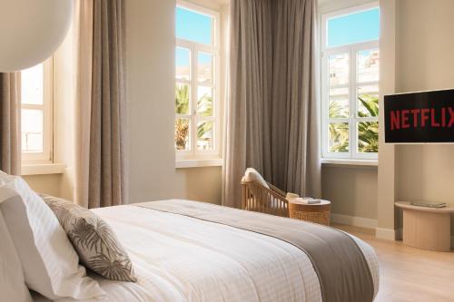 埃尔莫波利斯SYROS SOUL LUXURY SUITES的一间卧室设有一张床和两个窗户。