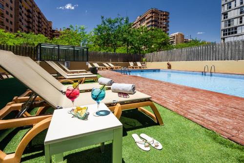 瓦伦西亚Hotel Valencia Oceanic Affiliated by Meliá的游泳池配有躺椅和桌子,并提供饮料