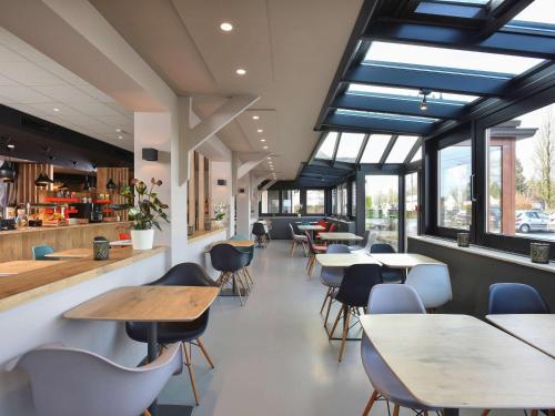 沙勒罗瓦沙勒罗瓦机场布鲁塞尔南宜必思酒店的餐厅设有桌椅和窗户。