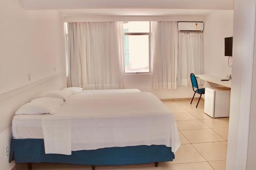 马塞约海湾海滩酒店的白色卧室配有白色的床和书桌