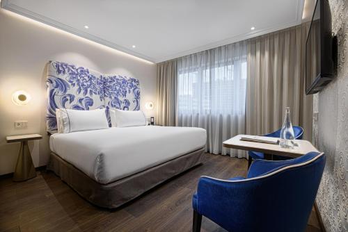 里斯本Eurostars Universal Lisboa的酒店客房带一张床、一张桌子和椅子