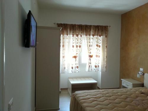 圣伊西多罗B&B sul Mare的一间卧室配有一张床、一台电视和一个窗口