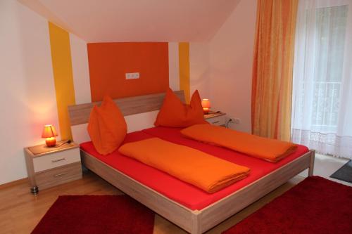 韦尔特湖畔克伦彭多夫Ferienwohnung am Wörthersee Villa Waldbach的一间卧室配有带橙色床单和橙色枕头的床