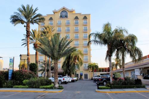 托雷翁波萨达德尔里奥贝斯特韦斯特快捷酒店的停车场内棕榈树的大型黄色建筑