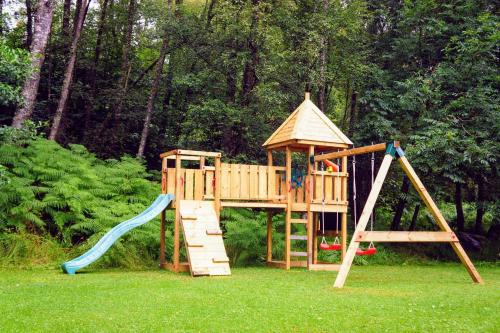 基林Cosy Rowan woodland lodge no1的一个带滑梯和游戏结构的木制游乐场