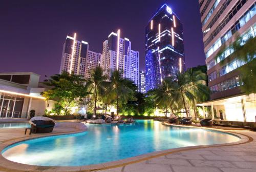 雅加达Wyndham Casablanca Jakarta的一座在晚上拥有城市天际线的大型游泳池