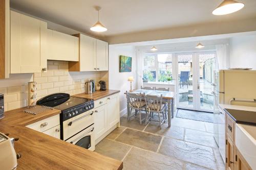 赫尔姆斯利Host & Stay - Willow Cottage的厨房配有白色橱柜、餐桌和用餐室