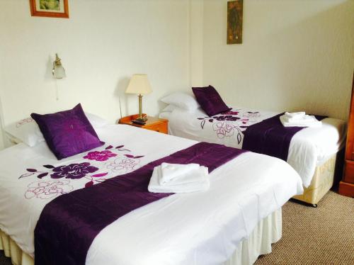 布莱克浦传奇酒店的配有紫色和白色床单的酒店客房内的两张床