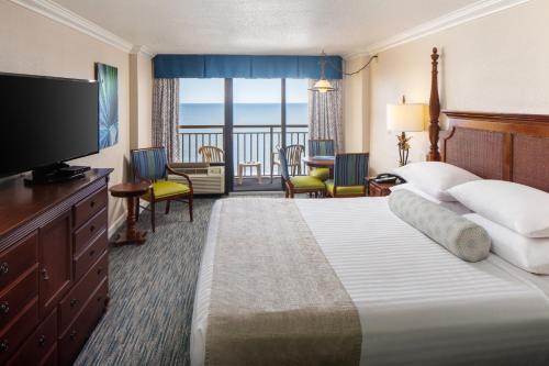 默特尔比奇Holiday Pavilion Resort on the Boardwalk的酒店客房设有一张大床和一台电视。