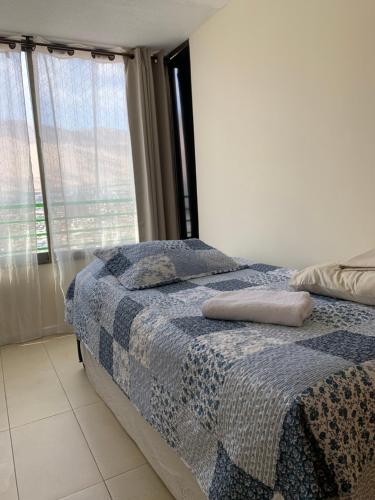 伊基克Magnolia apart Con facturas的一间卧室配有一张带蓝色毯子的床和窗户。