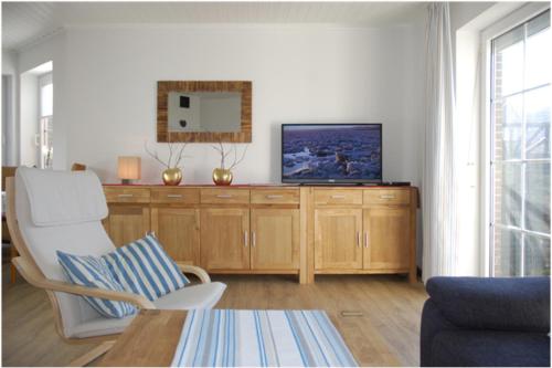 特希尔Haus Sandglöckchen的客厅配有木柜上的电视