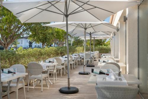 阿尔库迪亚港Trendhotel Alcudia - Adults Only的庭院里一排带白色遮阳伞的桌子