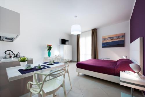 特拉帕尼西窗酒店的一间卧室配有一张紫色的床和一张桌子及椅子