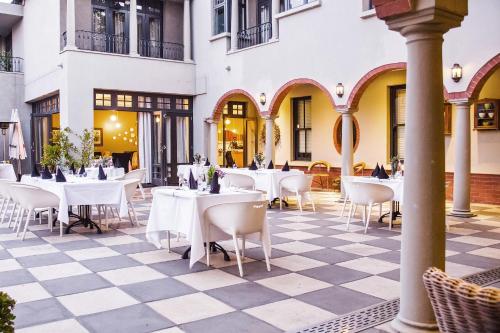 约翰内斯堡温斯顿酒店 的一间位于 ⁇ 板层的餐厅,配有白色的桌椅