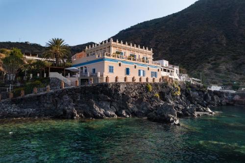雷妮Hotel L'Ariana ISOLE EOLIE - UNA Esperienze的水边悬崖上的房屋