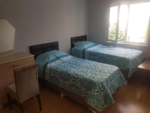 伊斯坦布尔Blue Appartment near to Istanbul new Airport的一间卧室配有两张床、一张桌子和一把椅子