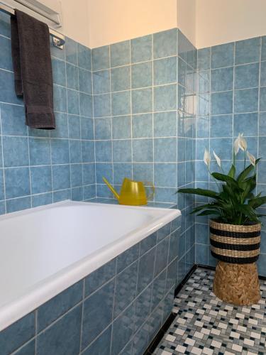 基姆湖畔贝尔瑙Ferienwohnung Das Inge De Unterne的蓝色瓷砖浴室设有浴缸和植物