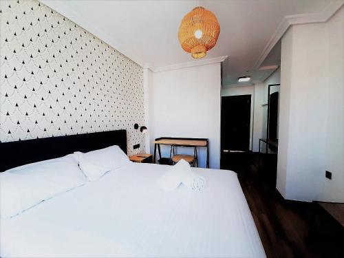 萨拉曼卡Hotel Matilde by gaiarooms的卧室配有白色的床和吊灯。