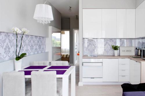 斯维诺乌伊希切Sunny Stay Apartment的厨房配有白色橱柜和紫色的桌椅