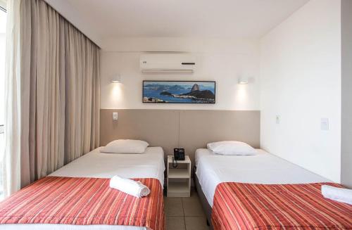 马卡埃Flat 1506 - Studio duplo em Macaé的酒店客房设有两张床,墙上挂着一张照片。