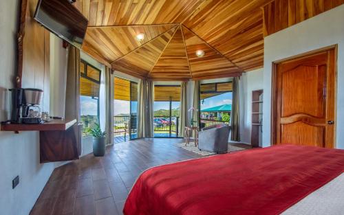 蒙泰韦尔德哥斯达黎加Hotel Trópico Monteverde的一间卧室配有一张大床和红色的床罩