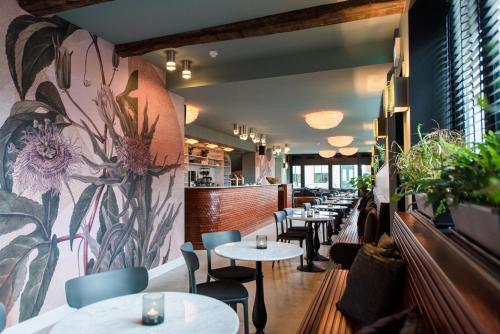 霍尔沃德Zee van Tijd Holwerd的餐厅设有桌椅和花卉壁画