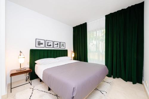 马德里Los Castaños Design Apartments in Conde Orgaz的一间卧室配有大床和绿色窗帘