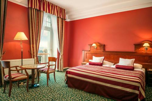 卡罗维发利Spa Hotel Imperial的酒店客房带一张床、一张桌子和椅子