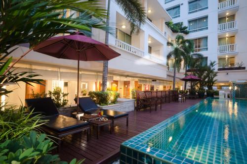 曼谷AT EASE saladaeng by AETAS的一个带椅子和遮阳伞的室外游泳池以及酒店