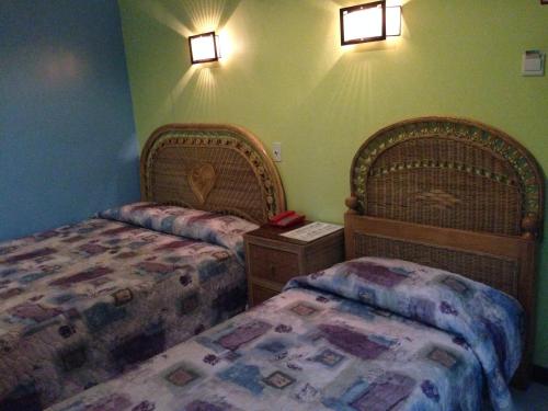 杜马格特RM宾馆的卧室配有两张床,墙上有灯